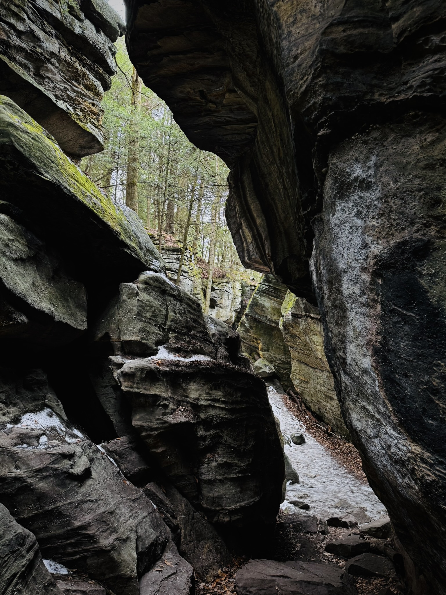 a rocky crevice between very large ledges. Ice covers the path through the crevice. 